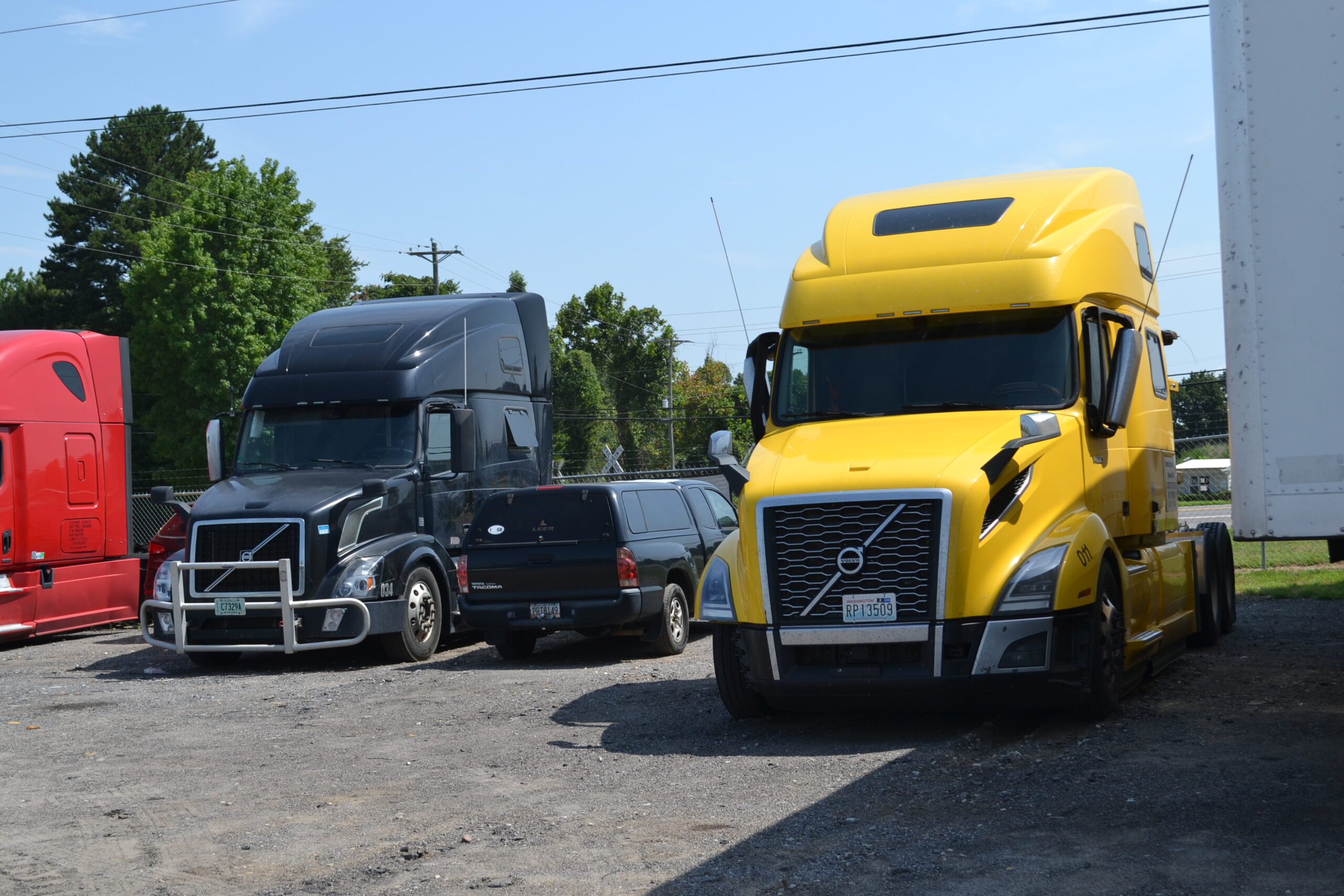 Parked heavy duty trucks, including a yellow and a black Volvo, at Big Wheels Repair in Gainesville, showcasing our repair and maintenance services.