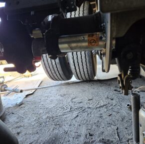 Underneath a truck, showing detailed work on the axle and brake components at Big Wheels Repair in Gainesville, highlighting heavy duty truck repair services