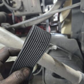 Mechanic holding a worn belt from a heavy duty truck at Big Wheels Repair in Gainesville, highlighting semi-truck maintenance services