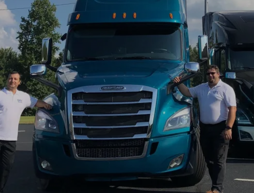 The two owners of Big Wheels Repair in Gainesville standing beside heavy duty trucks, showcasing their repair and maintenance services.