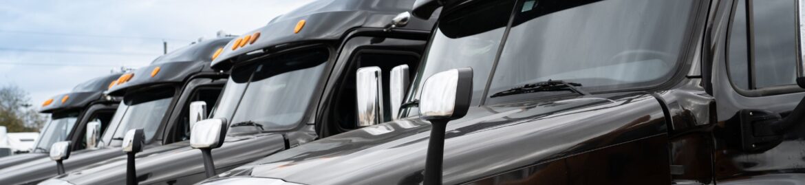 Close-up view of a row of black semi-trucks parked side by side at Big Wheels Repair Gainesville, GA